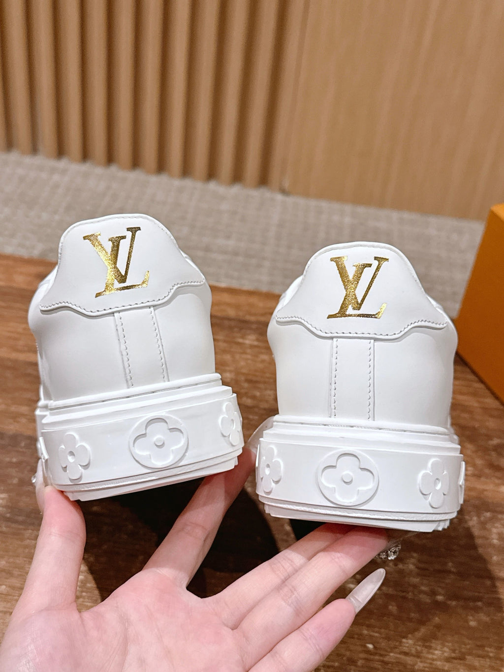 White Louis Vuitton sneakers back view with gold LV marks and cushioned heel