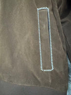 Brown jacket detail: rectangular flap pocket with white braided trim