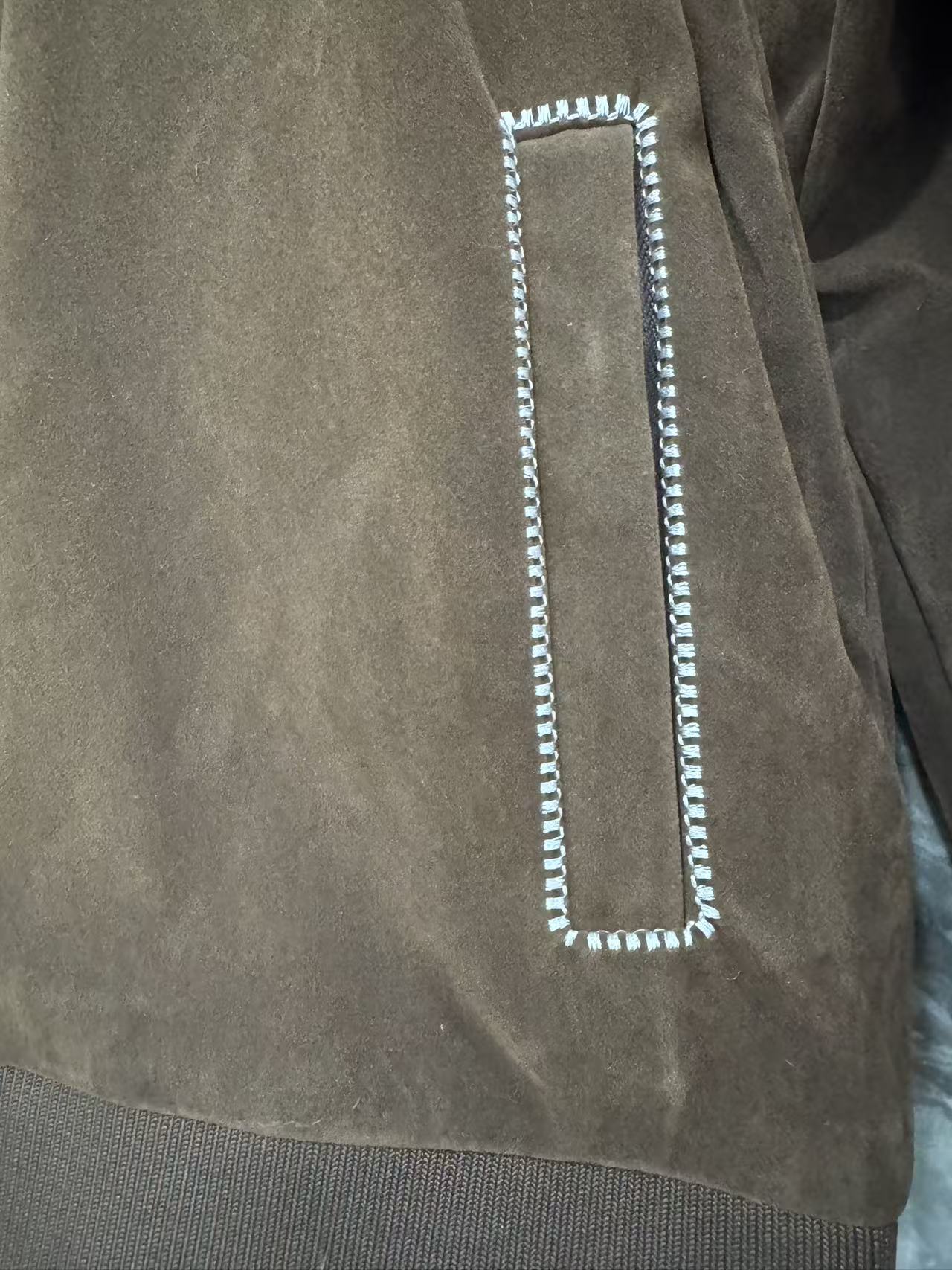 Brown jacket detail: rectangular flap pocket with white braided trim