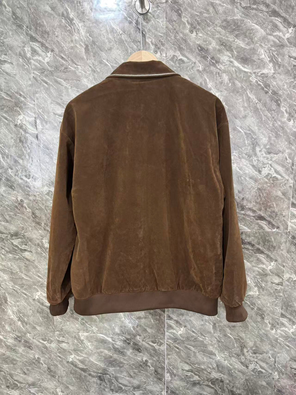 Brown jacket back view with full-length seams and zip closure at hem