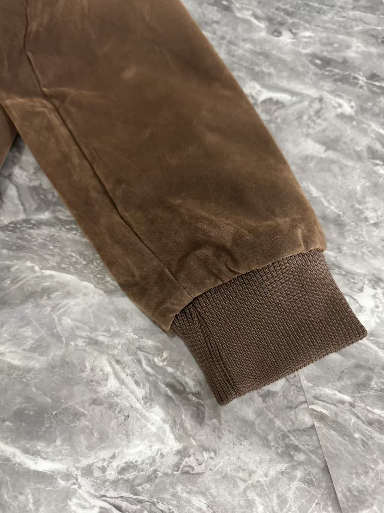 Brown jacket sleeve with ribbed knit cuff and visible seam stitching