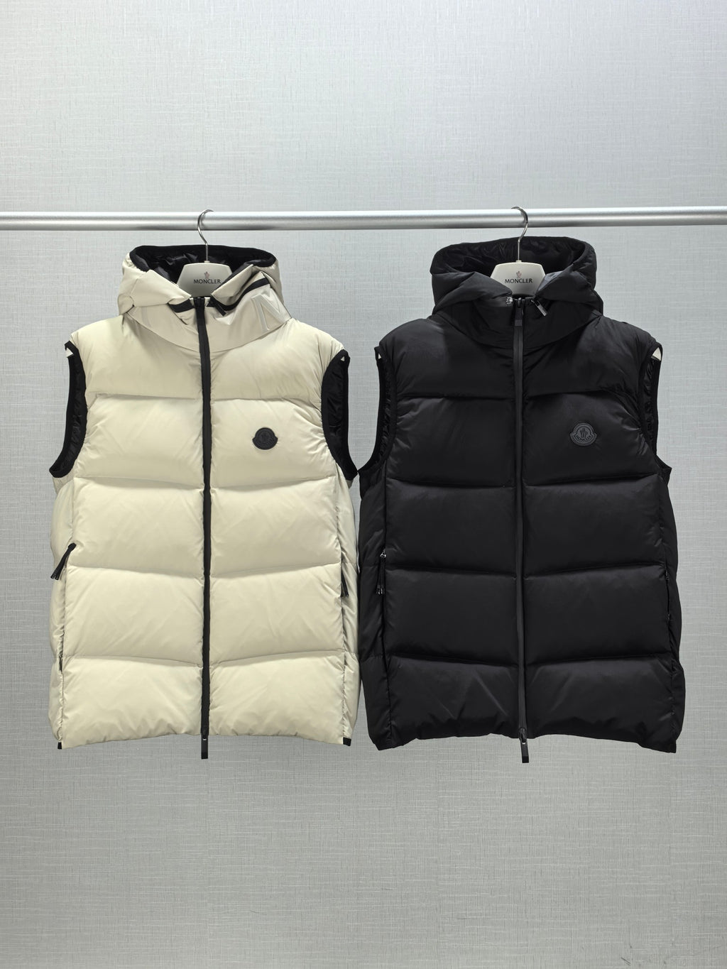 Quilted hooded puffer vests in light cream and black, zip-front with logo patch