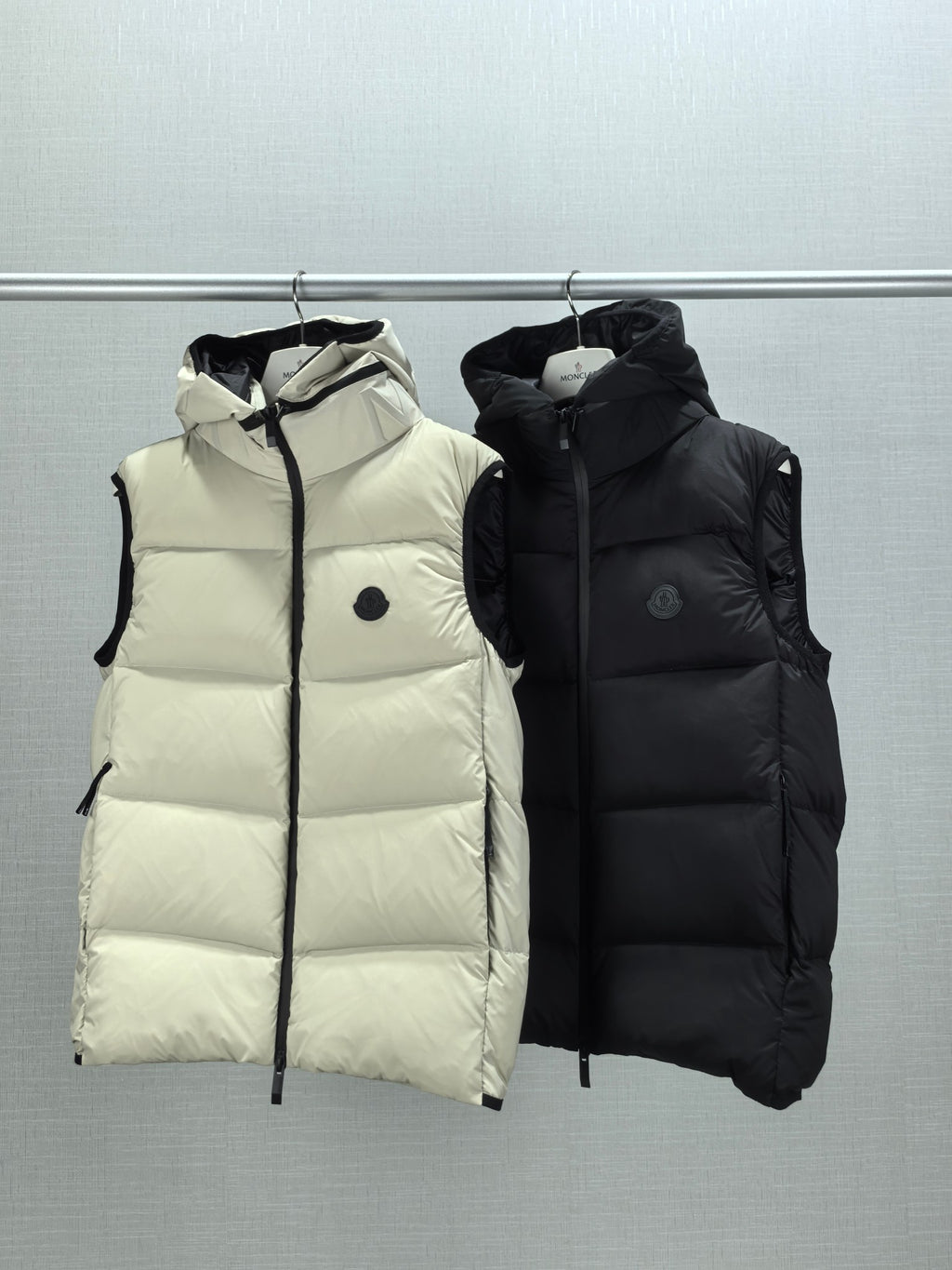 Quilted hooded puffer vests in light cream and black, standing collar and zip-front