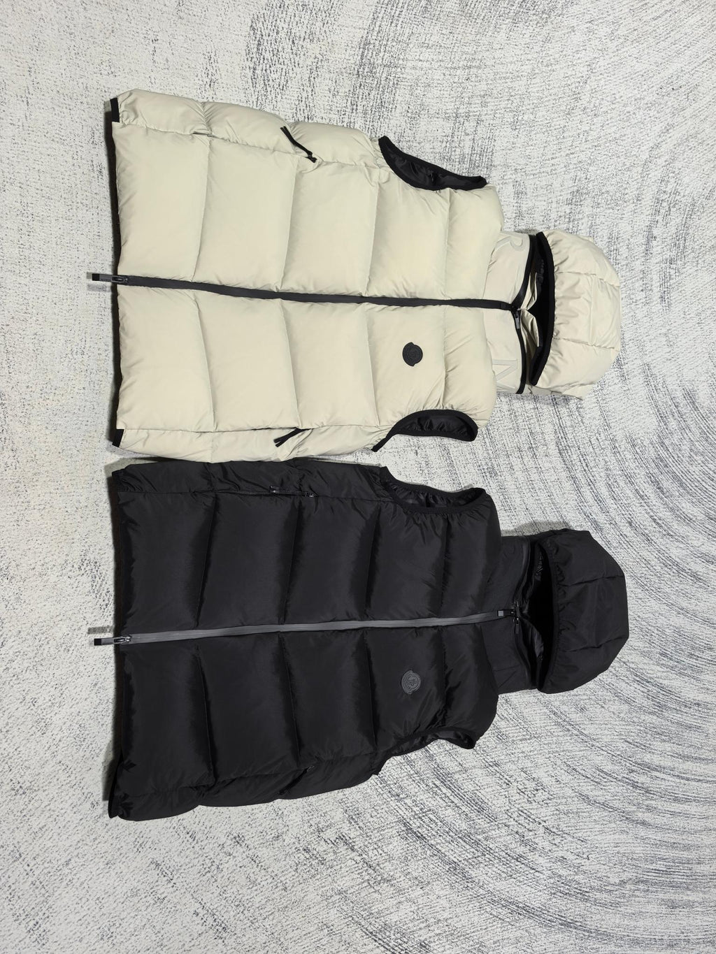 Sleeveless quilted puffer vests in light cream and black, side view with hoods
