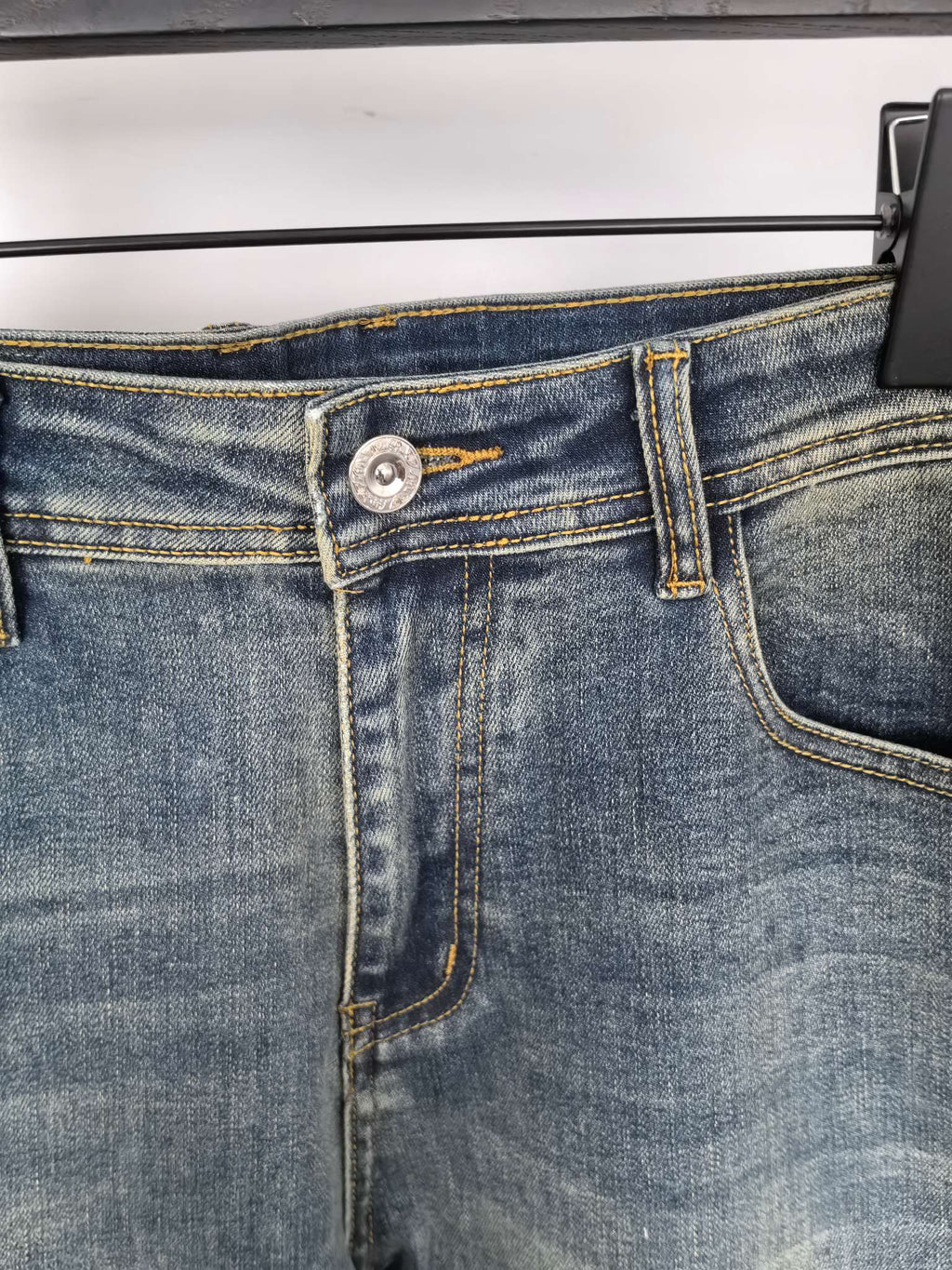 Prada denim pants waistband close-up with button and stitched fly