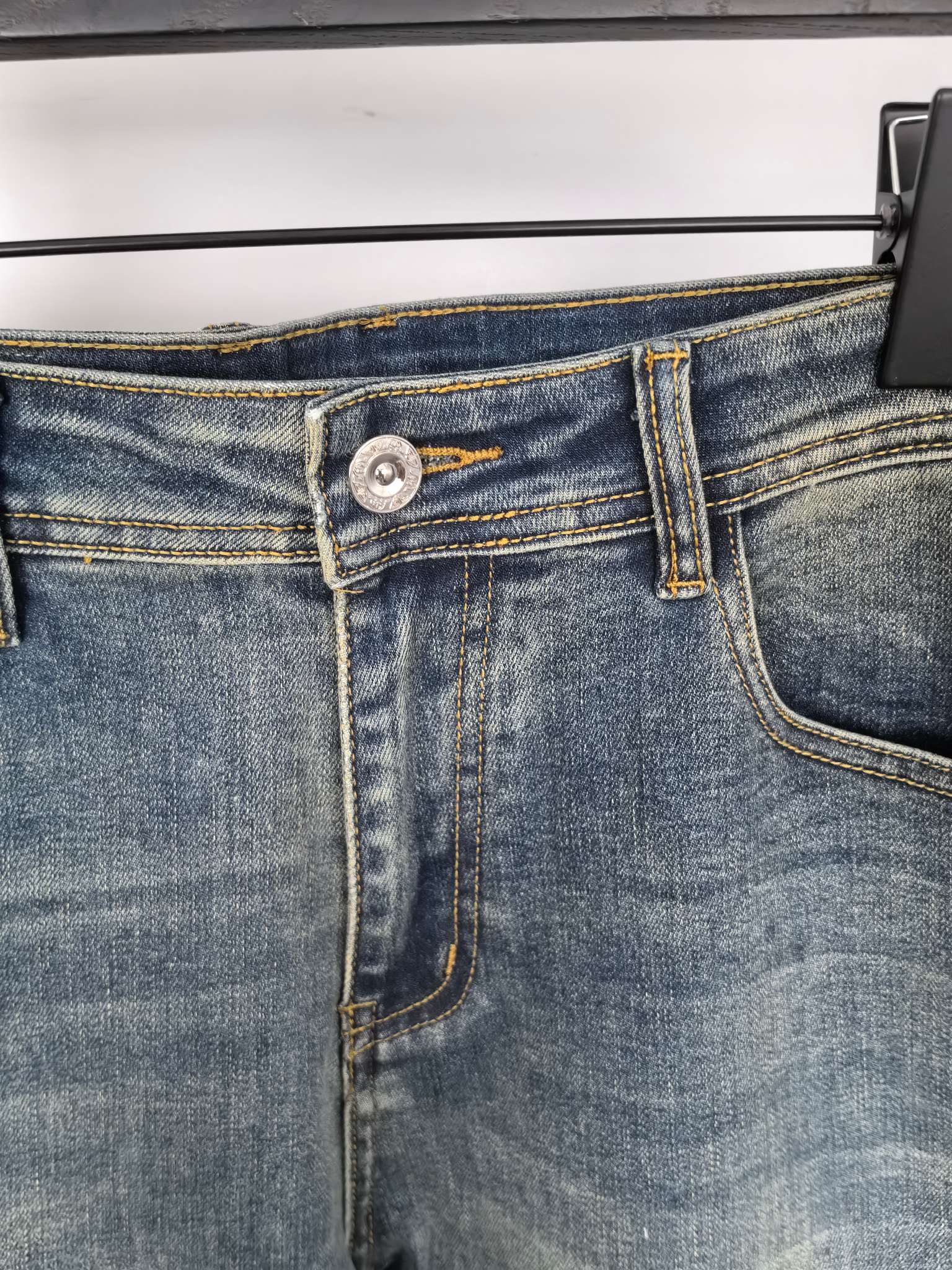 Prada denim pants waistband close-up with button and stitched fly