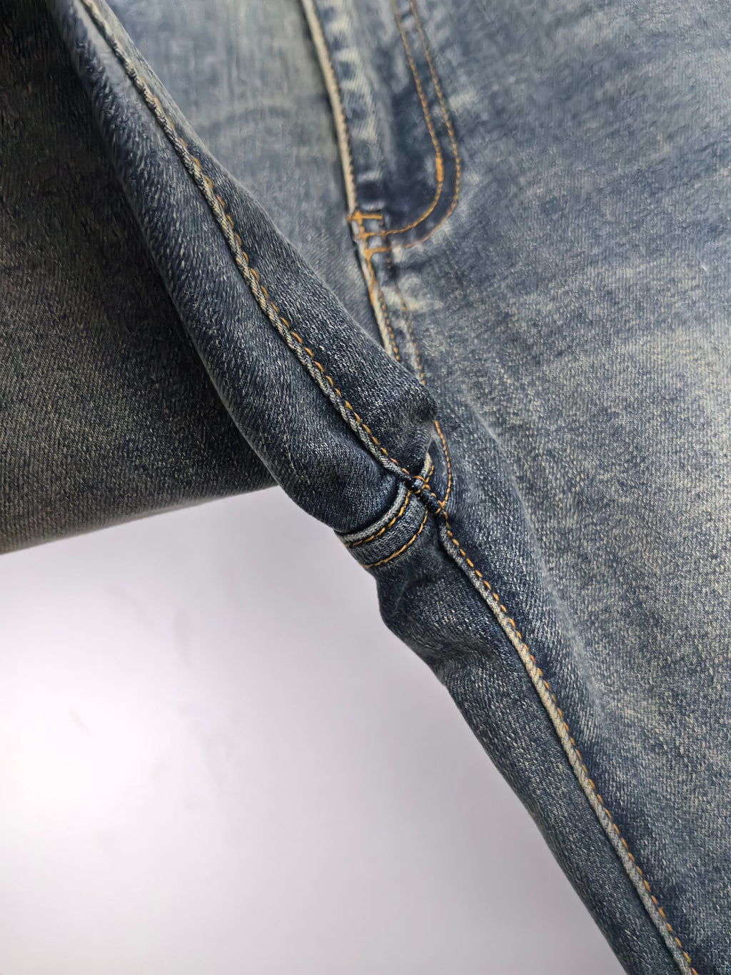 Prada denim pants side seam close-up with contrast yellow stitching