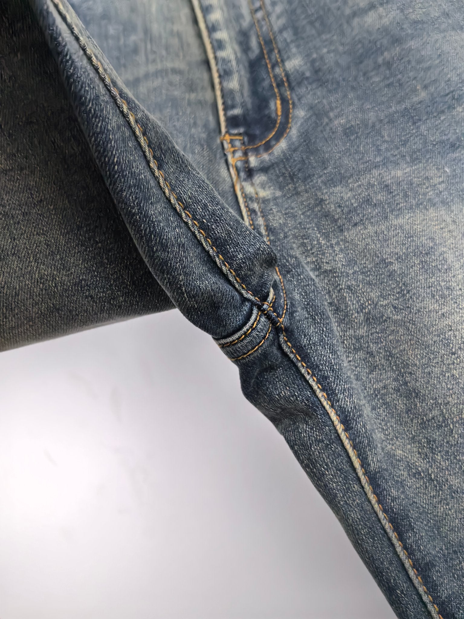 Prada denim pants side seam close-up with contrast yellow stitching