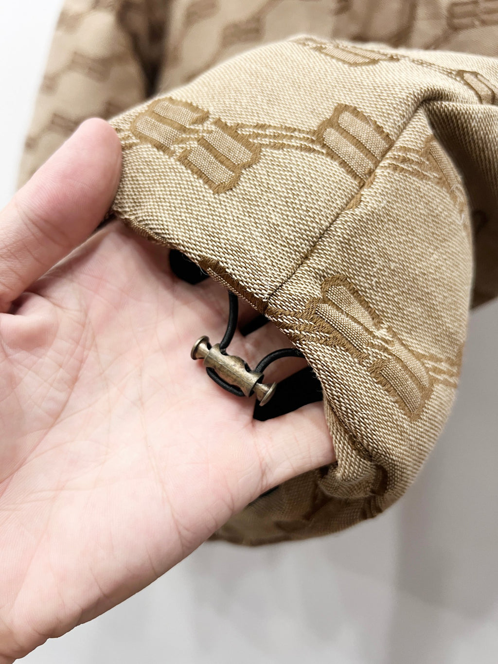Balenciaga puffer jacket cuff close-up in beige with logo pattern and metal snap