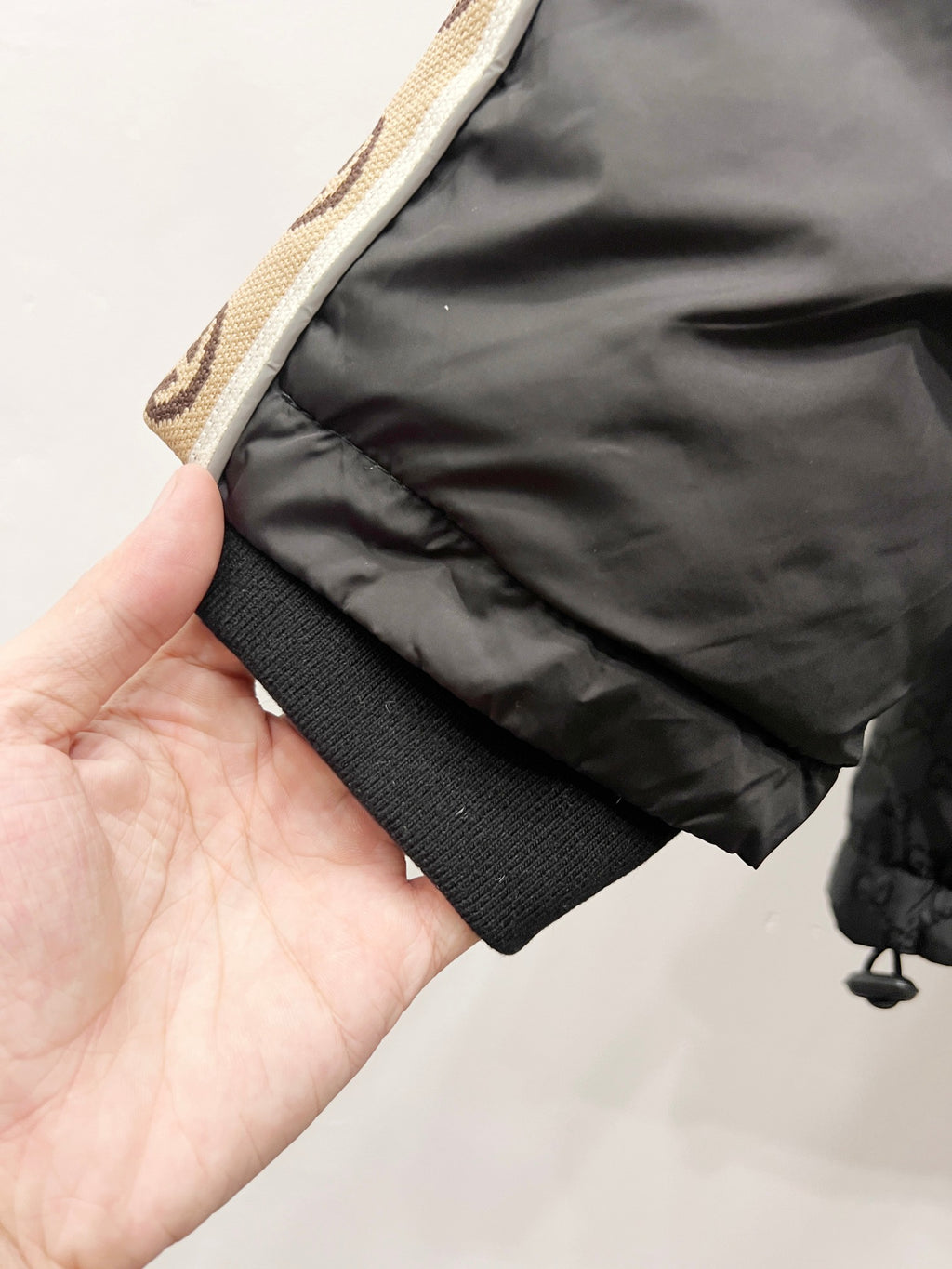 Dark puffer jacket cuff and hem with quilted layers and textured band