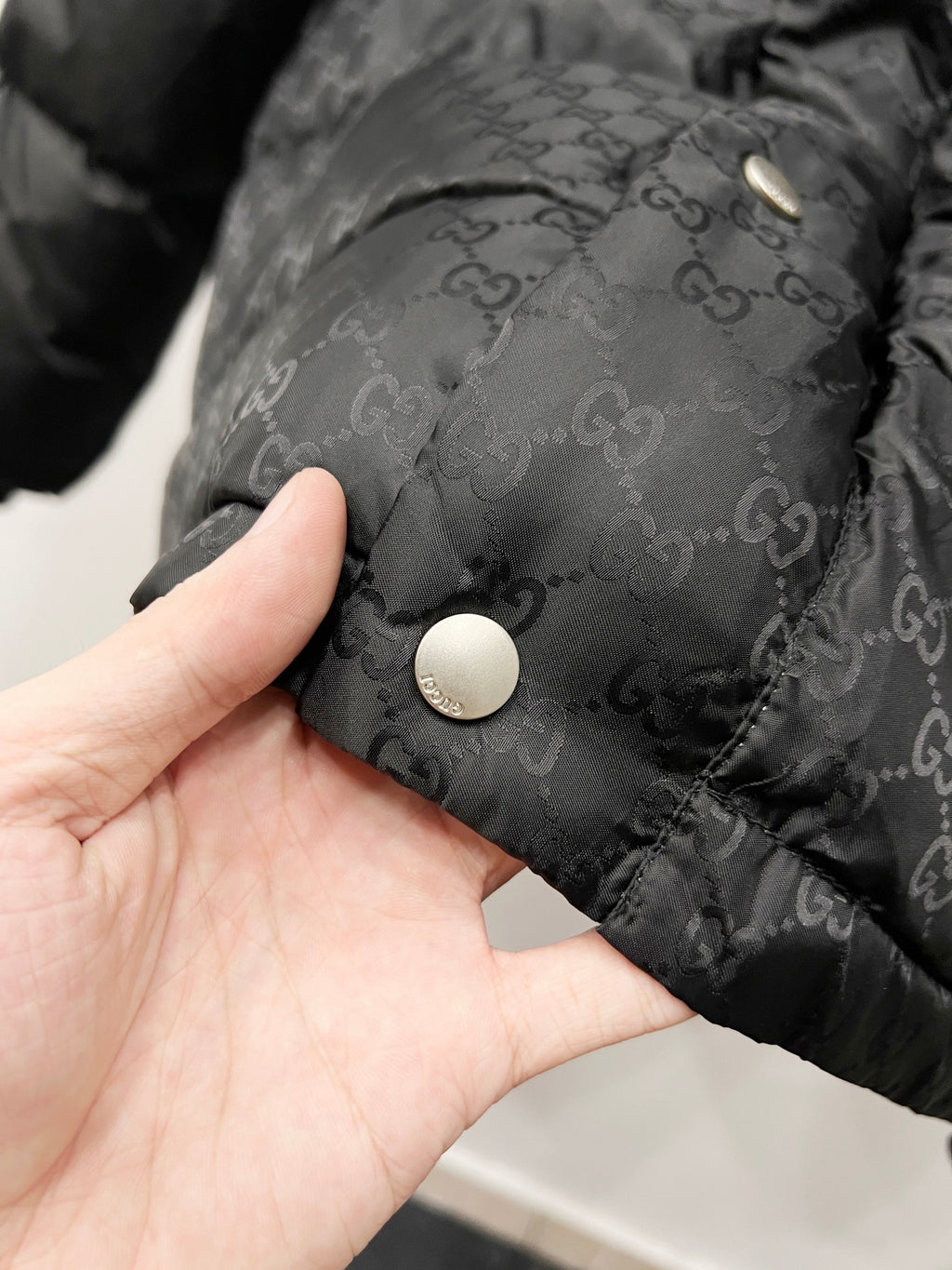 Dark hooded puffer jacket fabric with round snap button and monogram texture