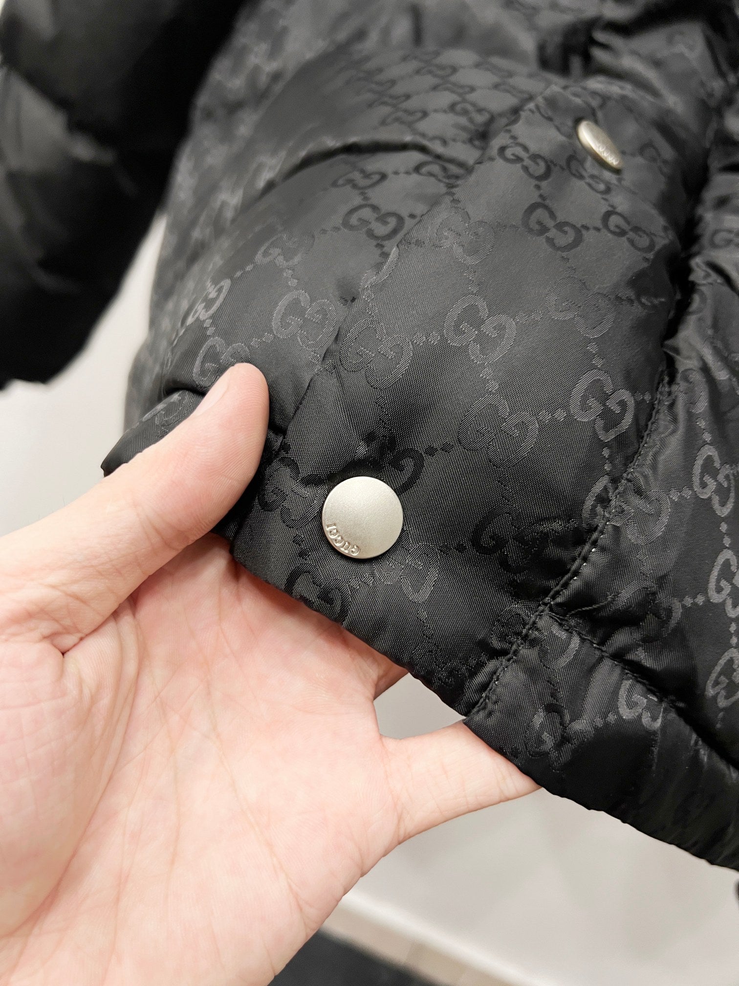 Dark hooded puffer jacket fabric with round snap button and monogram texture