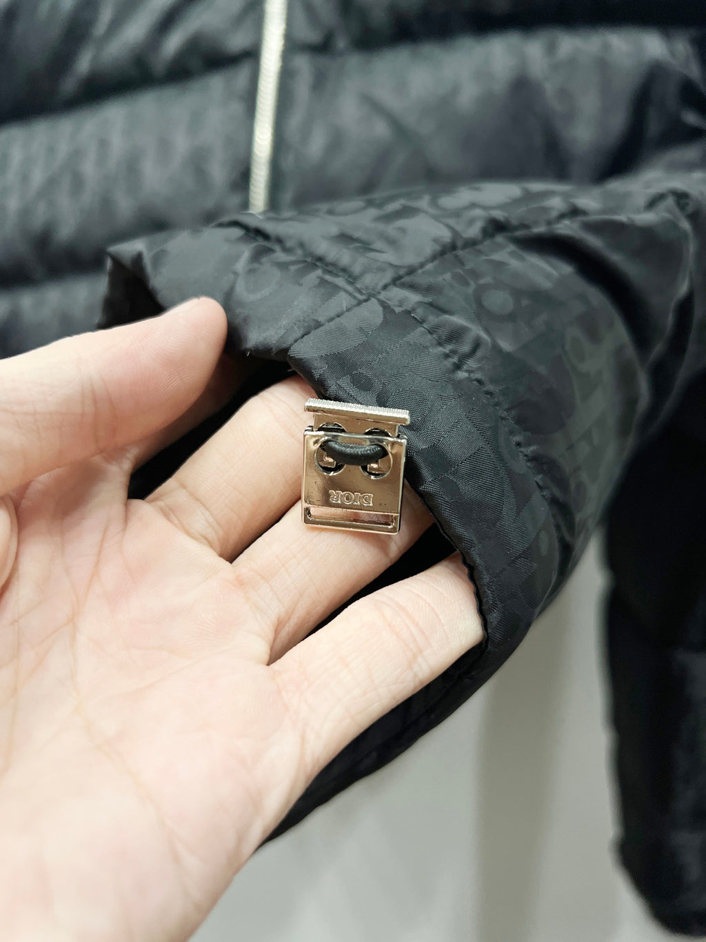 Quilted puffer jacket close-up with metal brand tag and zipper