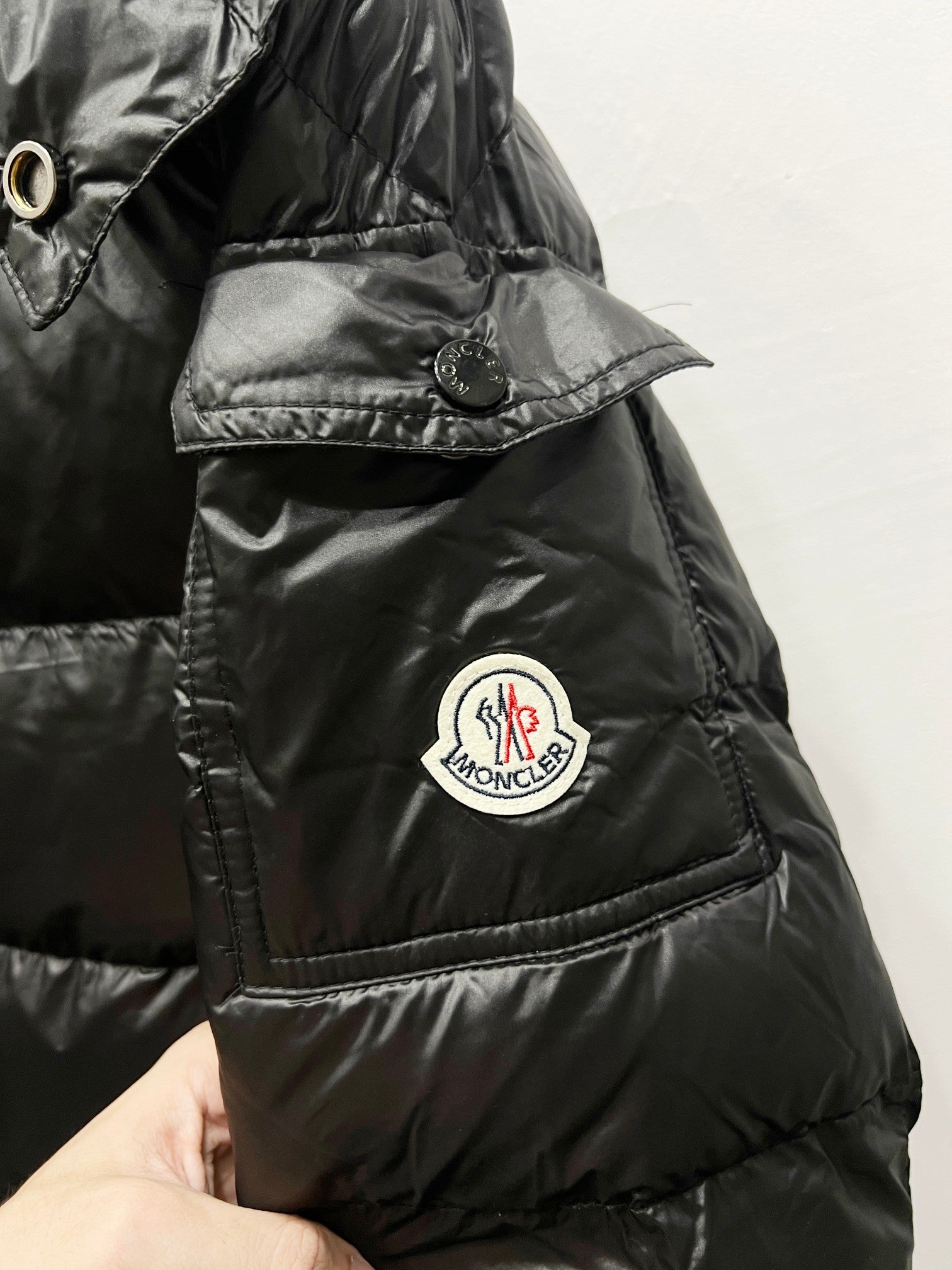Moncler puffer jacket detail, dark black, round logo badge and quilted panels