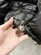 Moncler puffer jacket close-up, dark black zipper pull with logo tag
