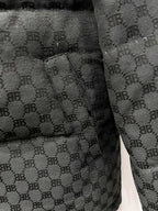 Dark gray puffer jacket sleeve cuff with quilted monogram fabric and stitched seam