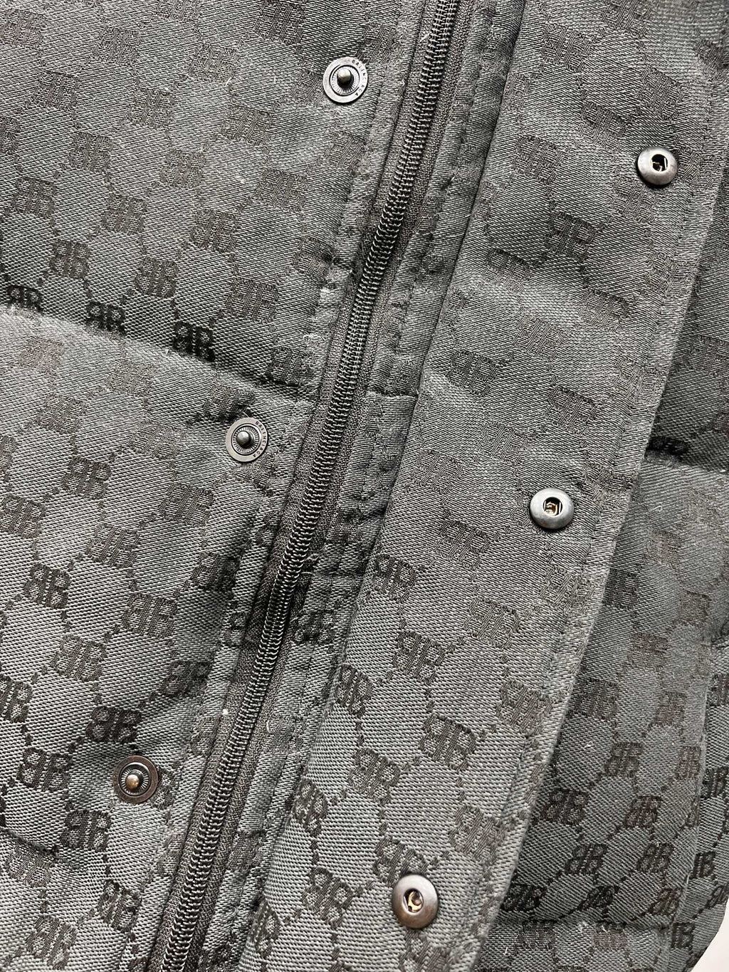 Dark gray puffer jacket front with metal zipper and snap buttons on placket