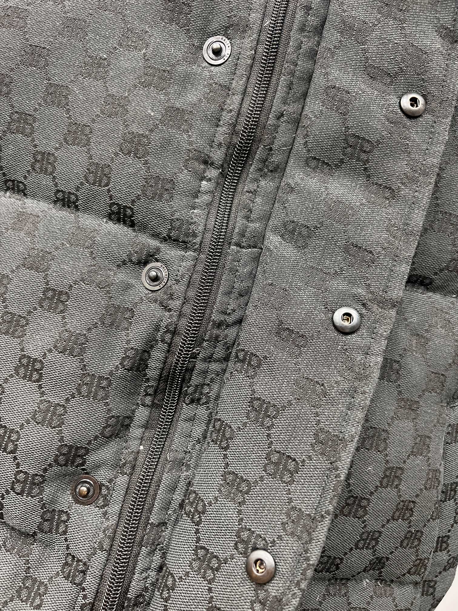 Dark gray puffer jacket front with metal zipper and snap buttons on placket