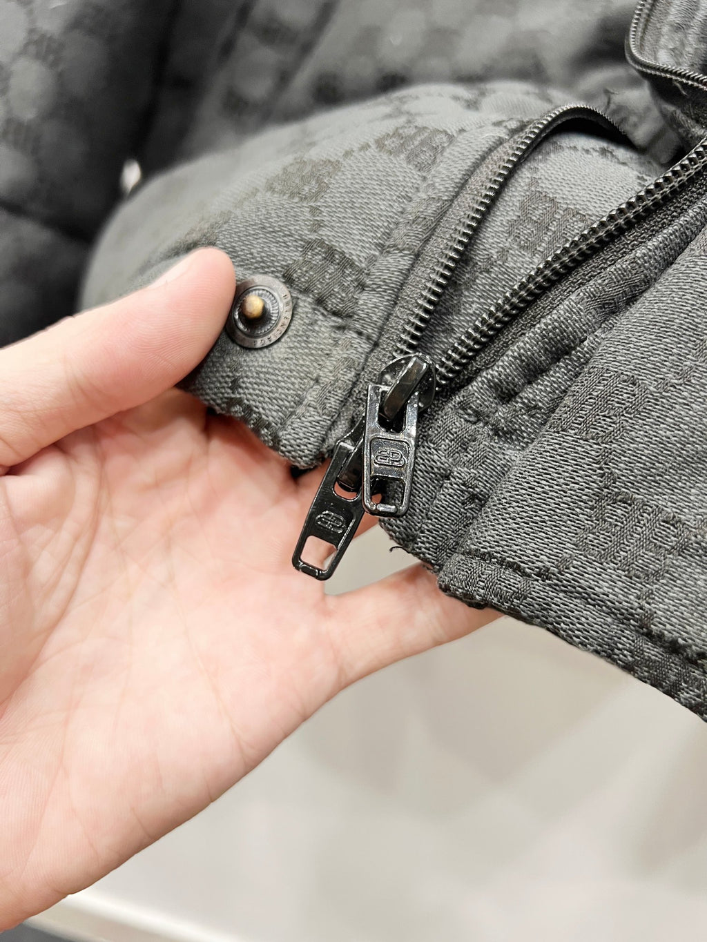 Dark gray puffer jacket cuff with zipper and buttoned strap detail