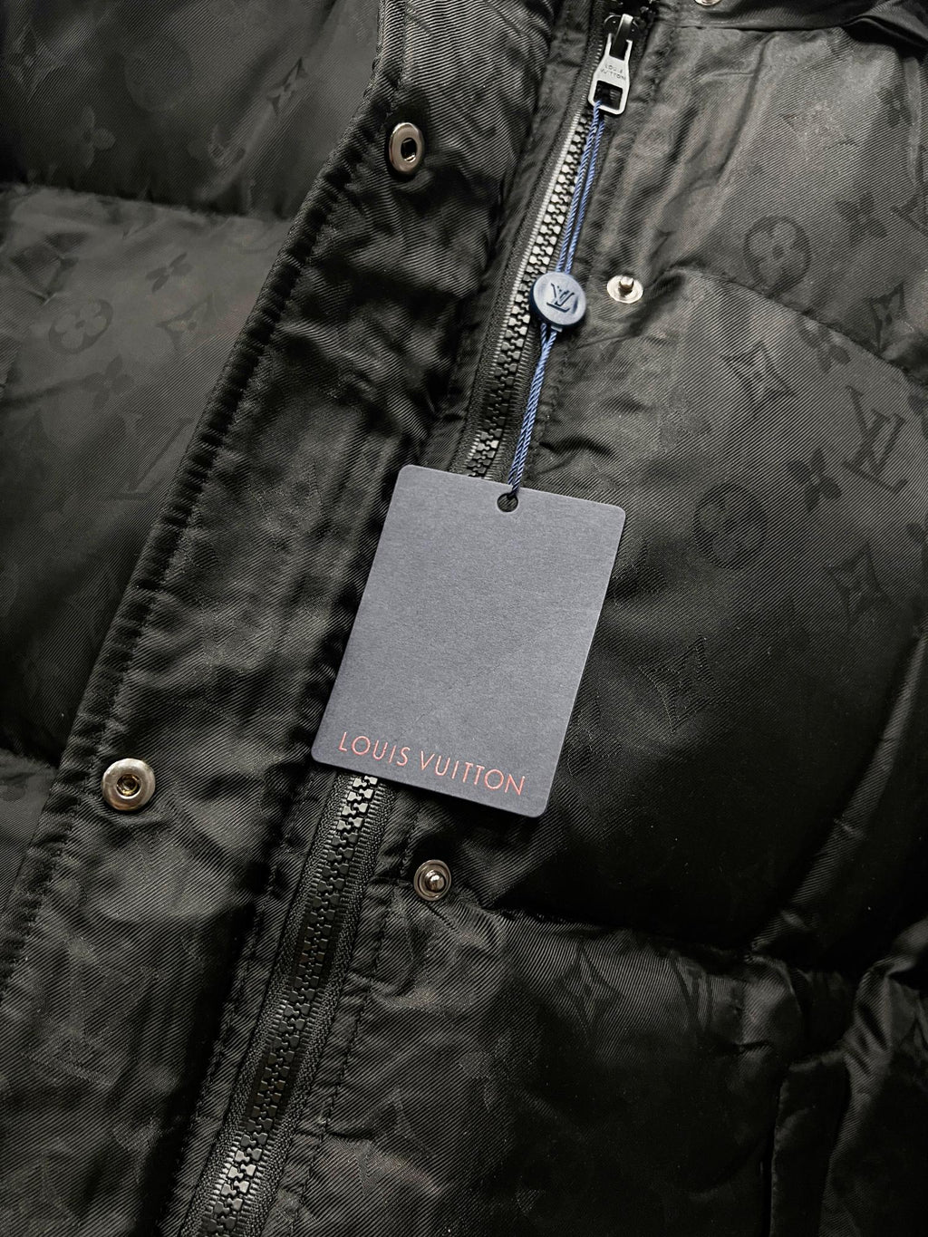 Black puffer jacket zip with Louis Vuitton-branded hanging tag