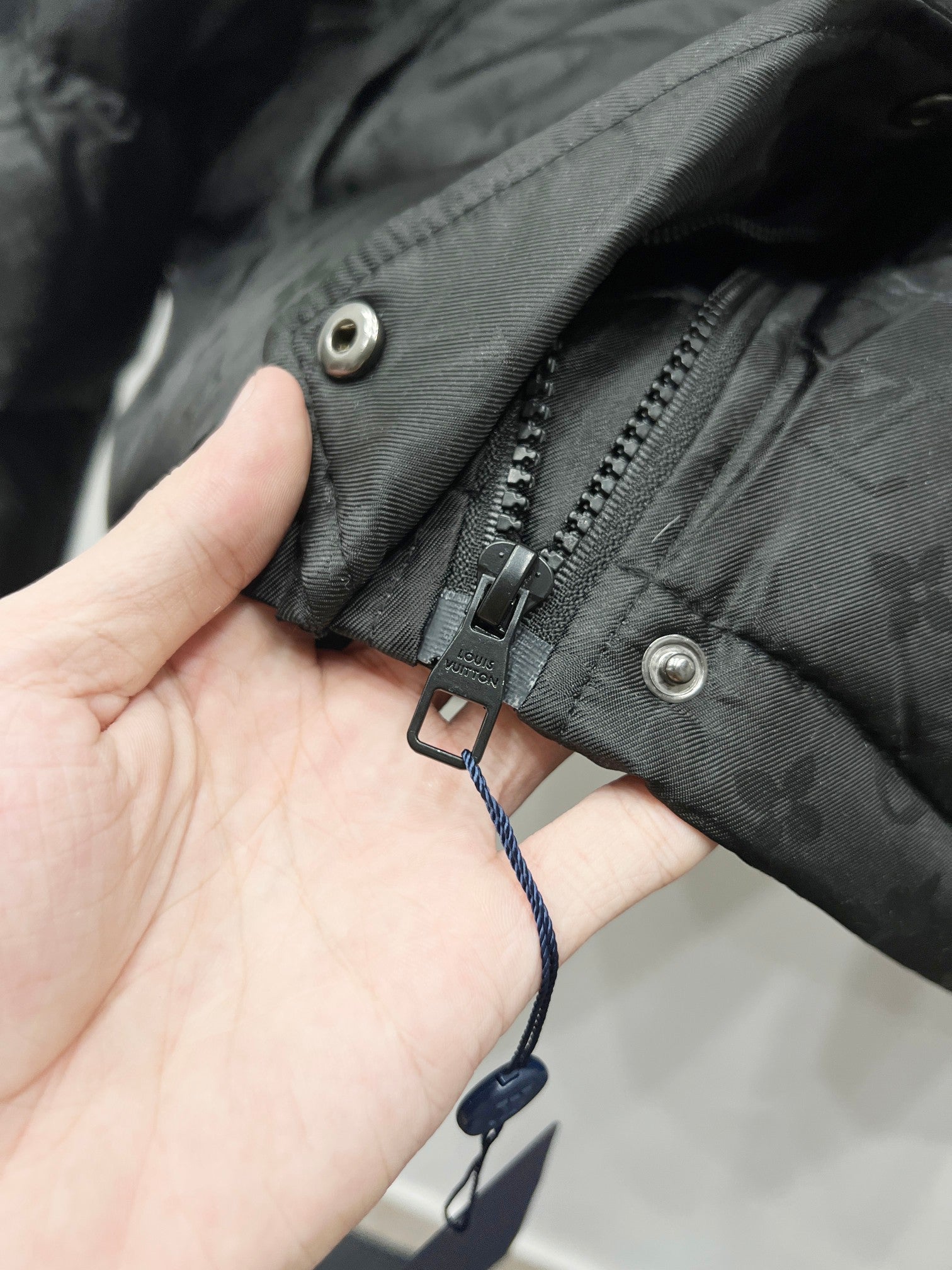 Black hood puffer jacket cuff with zipper pull and adjustable strap