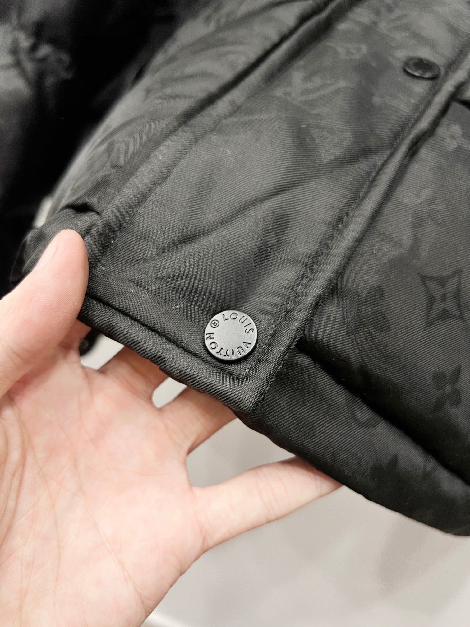 Black hooded puffer jacket cuff with snap and circular logo patch