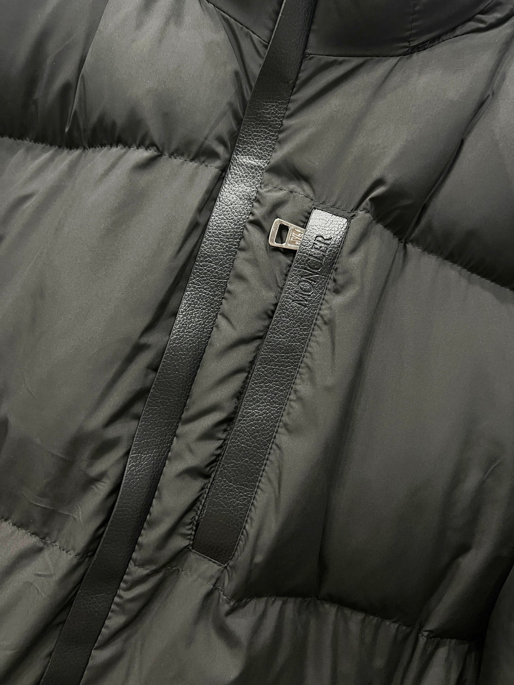 Moncler long puffer jacket zipper with logo pull tab on quilted dark fabric