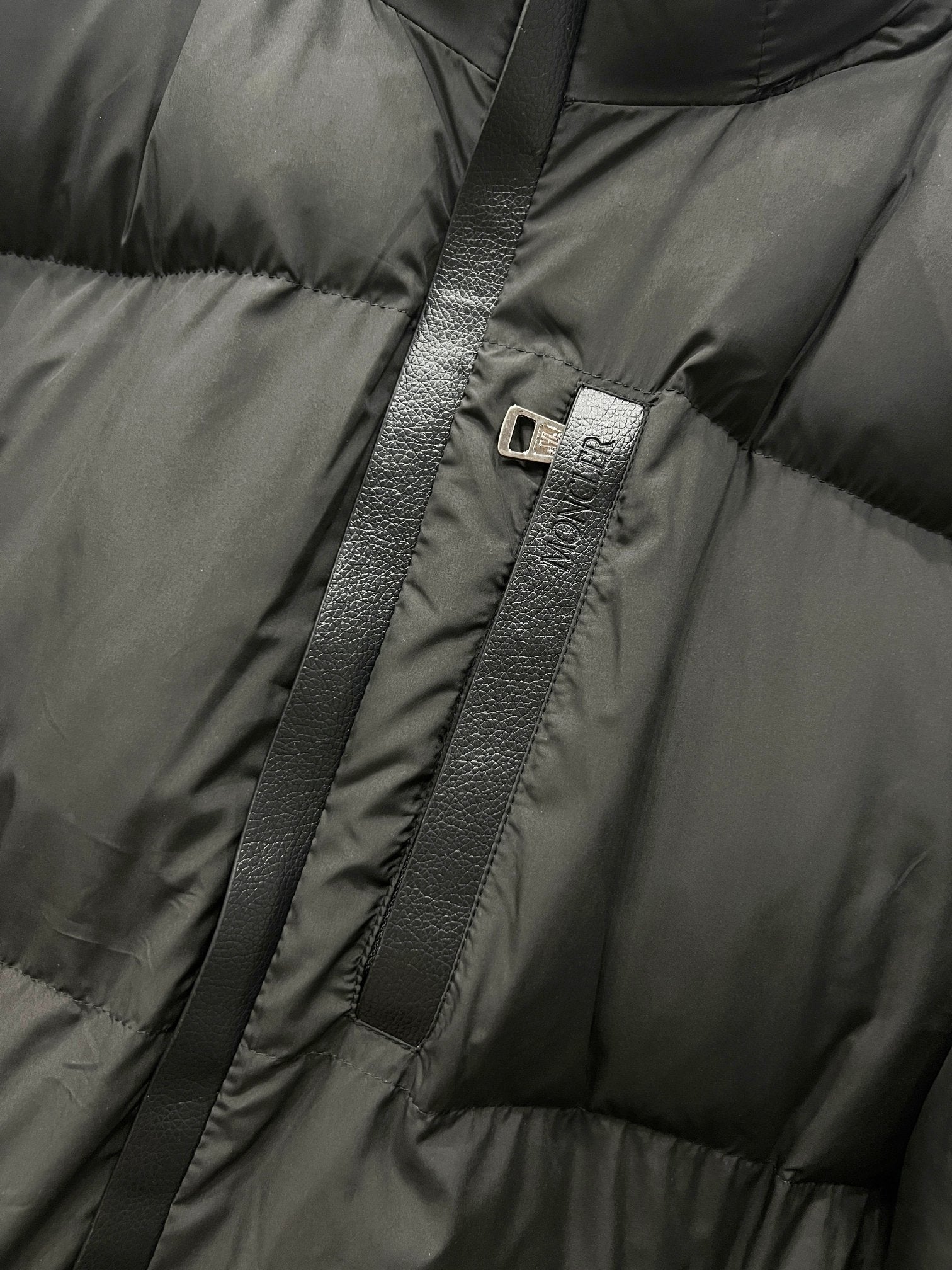Moncler long puffer jacket zipper with logo pull tab on quilted dark fabric