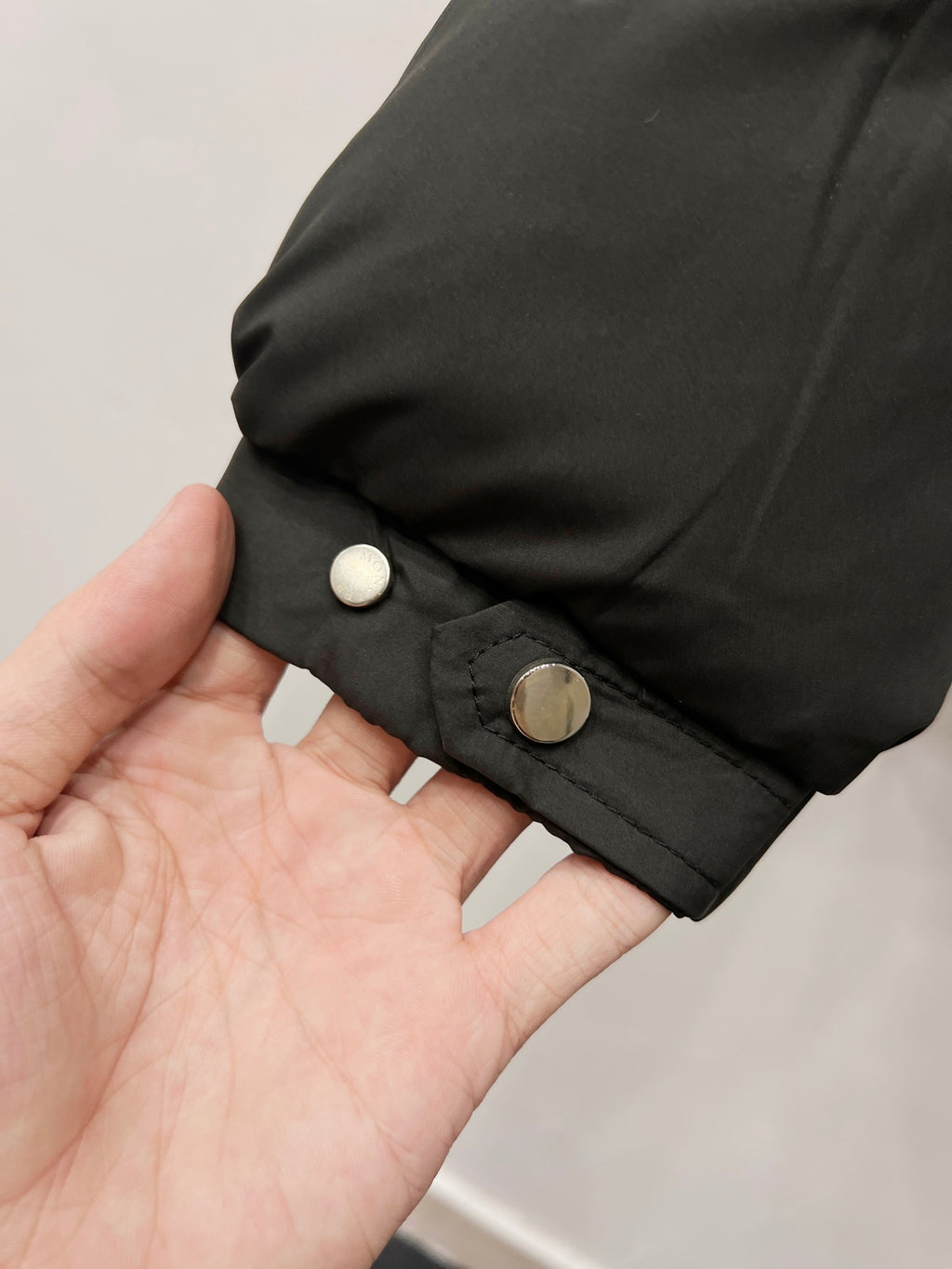 Moncler long puffer jacket cuff with snap button on dark padded sleeve