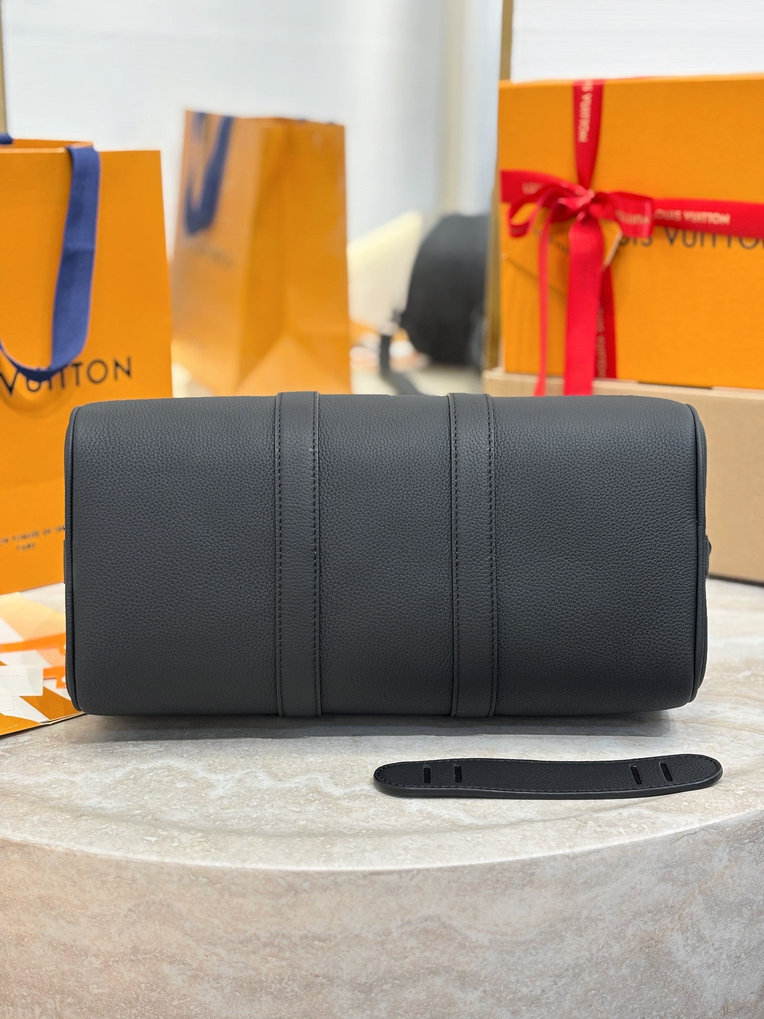 Louis Vuitton leather duffel bag with top handles, vertical stitching, dark gray.