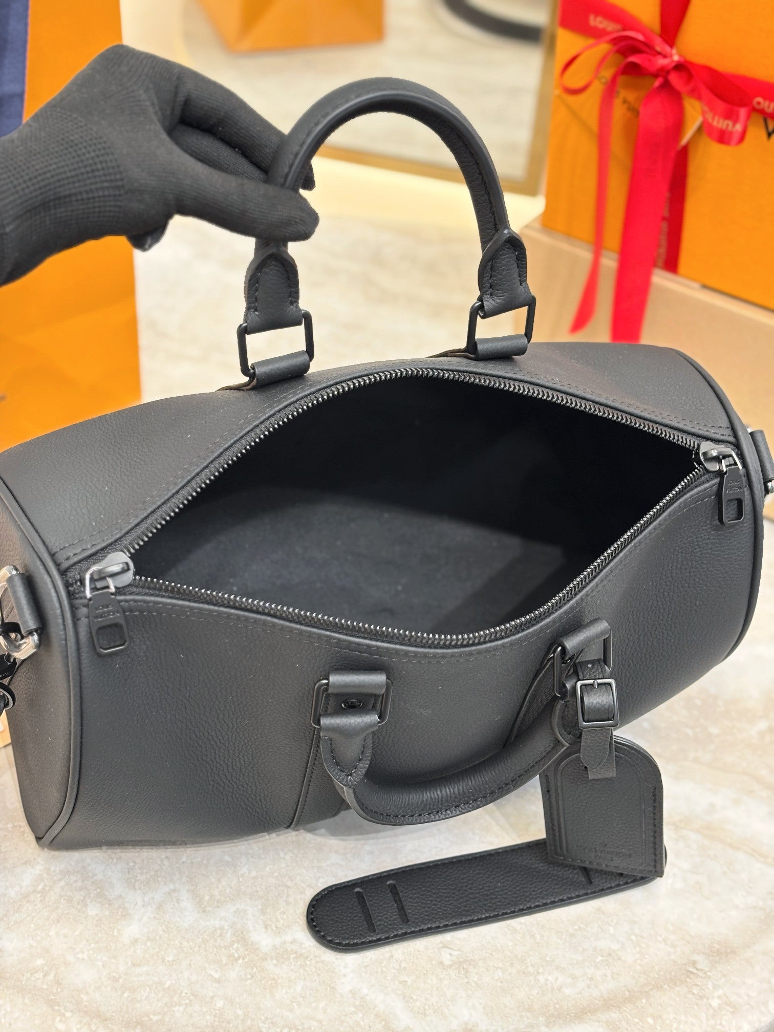Louis Vuitton leather bag with top zip open, showing interior, dark gray.