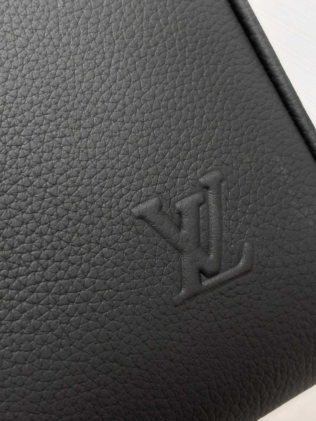 Louis Vuitton logo embossing on grained leather, dark gray.