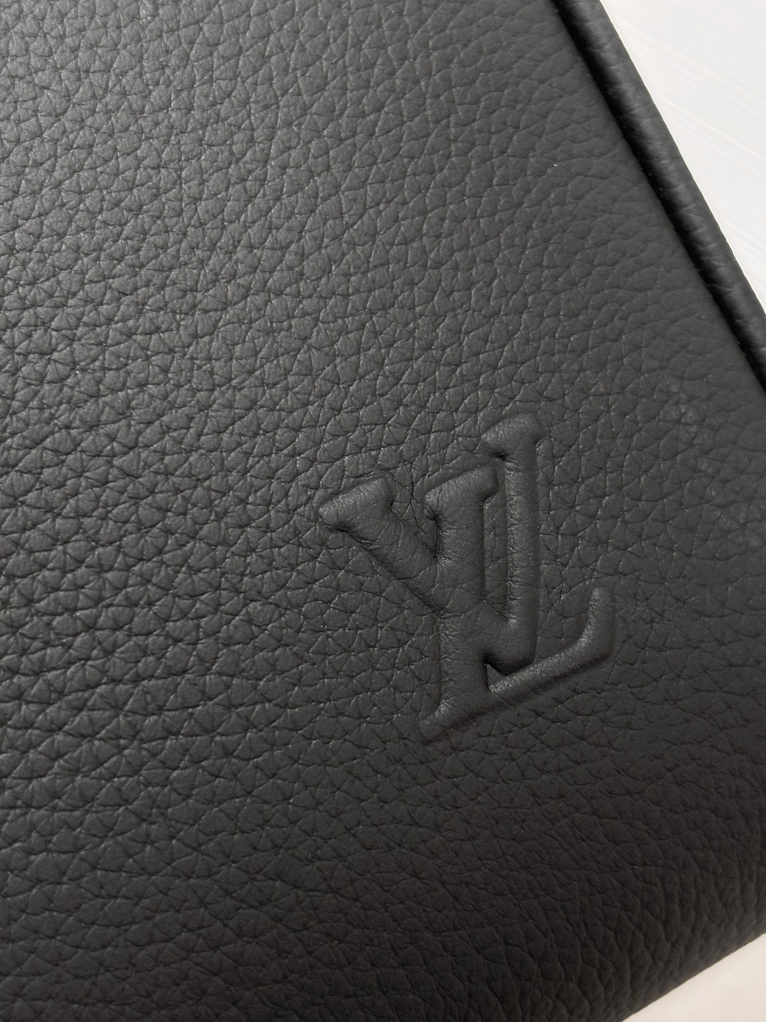 Louis Vuitton logo embossing on grained leather, dark gray.