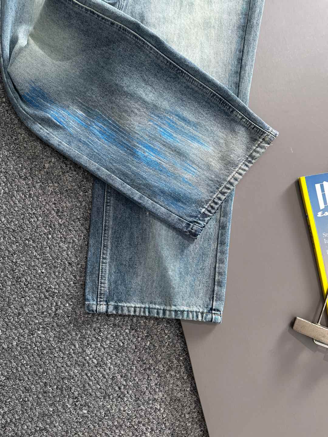 Folded light blue denim jeans with washed blue pattern on the knee area, straight leg