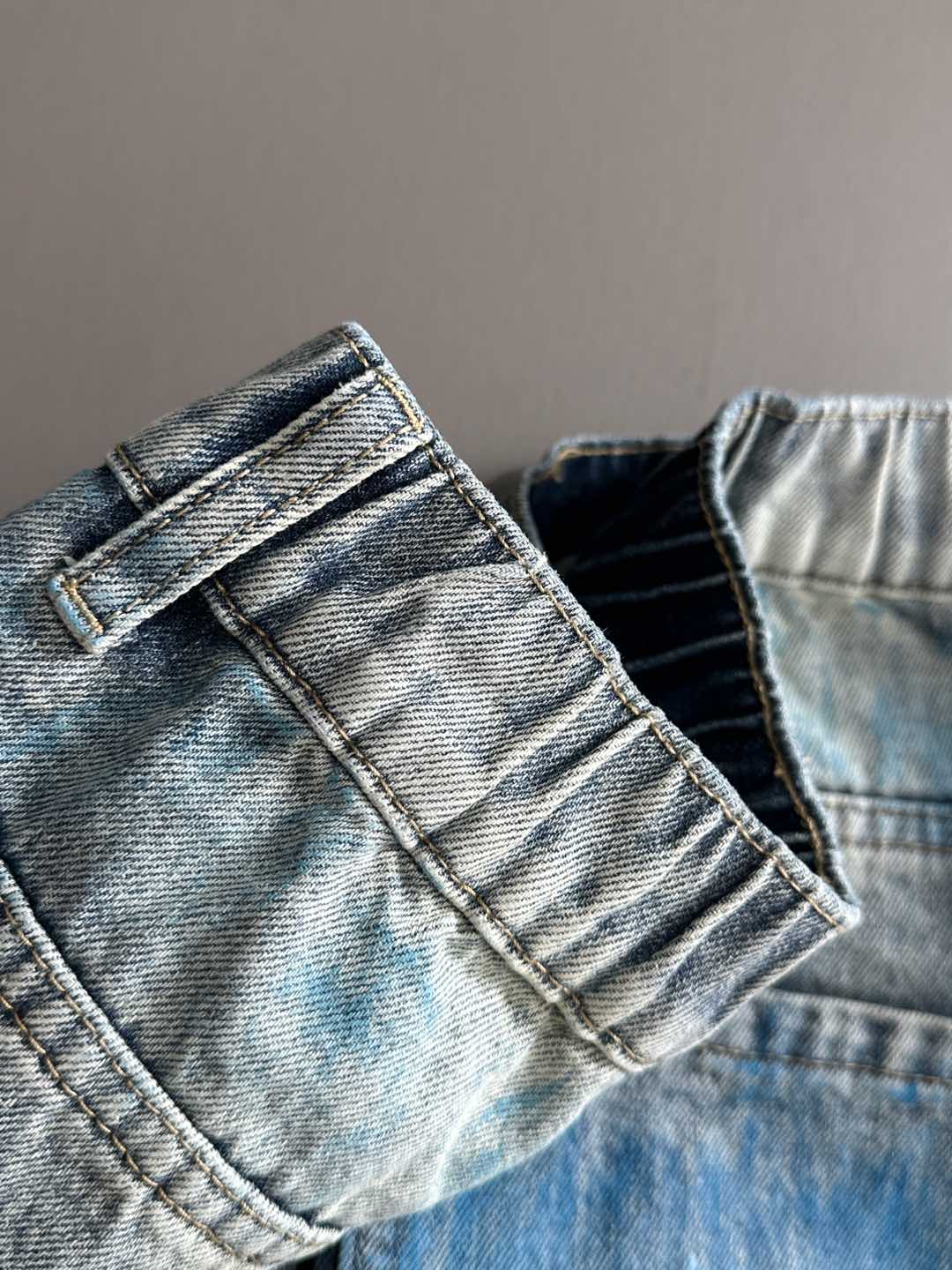 Denim jeans back yoke with belt loops and stitched seams; light blue wash