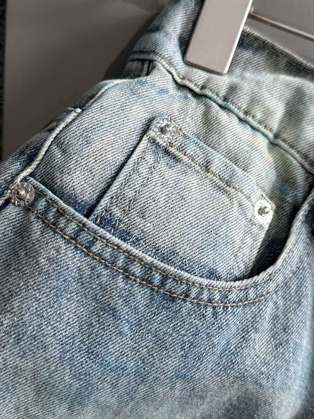 Light blue denim jeans detail: front button, curved pocket opening, belt loops
