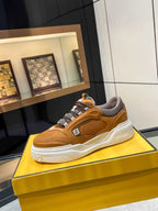 Tan Fendi sneakers on yellow box, low-top lace-up with gray collar and sculpted white sole.