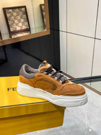 Tan Fendi sneakers on yellow box, lace-up with gray strap detail and white platform sole.