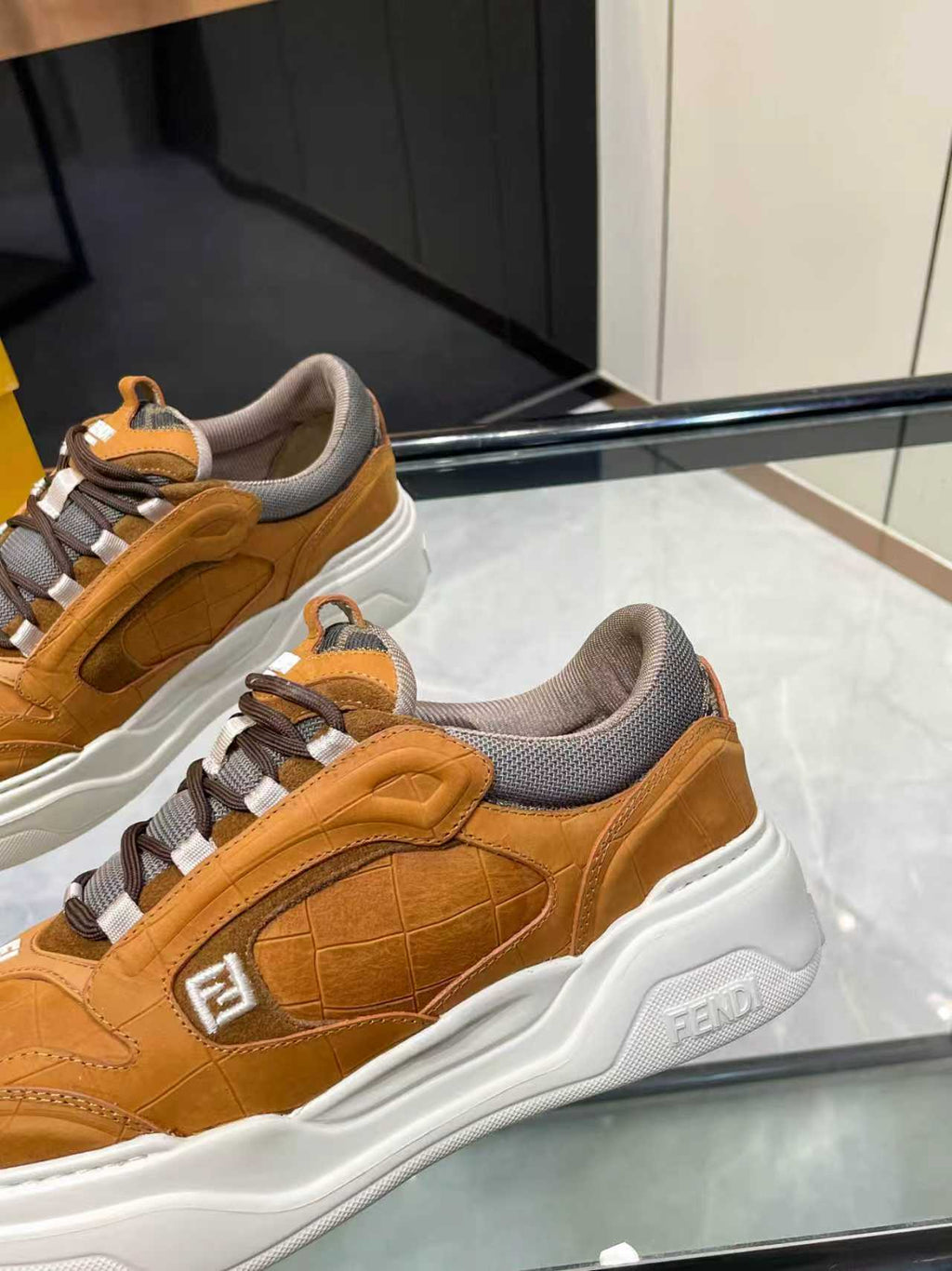 Brown Fendi sneakers close-up, lace-up straps and white sole with logo patch.