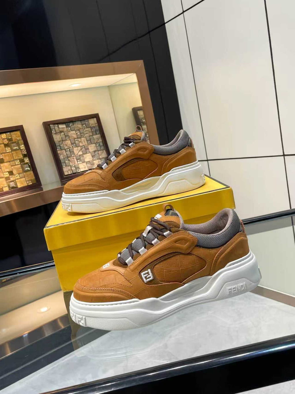 Tan-brown Fendi sneakers on yellow display boxes, side-by-side view with thick white soles.