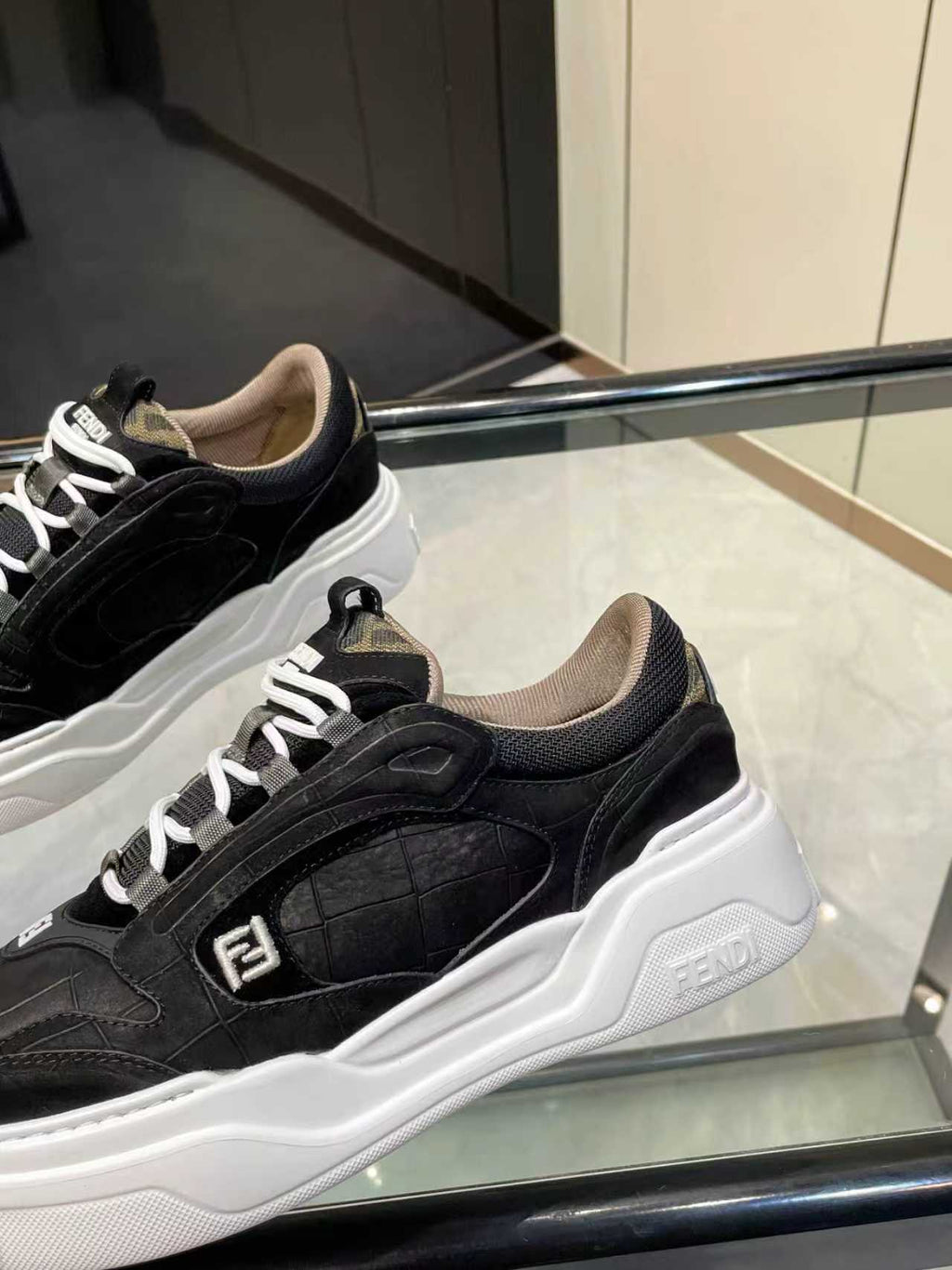 Close-up of black lace-up sneakers with white chunky sole and Fendi logo