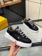 Black lace-up sneakers held in hand, white chunky sole with Fendi logos