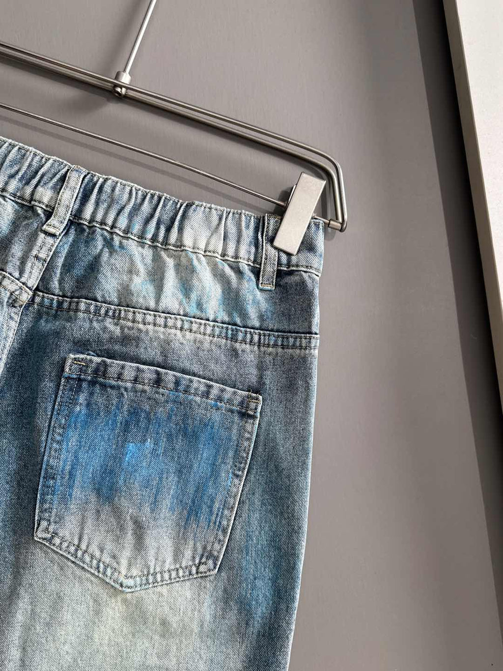 Light blue denim jeans with back pocket and stitched panel details, belt loops