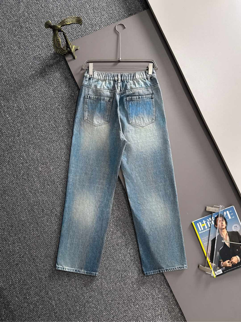 Light blue denim jeans with black logo on front leg, wide cropped fit, button fly