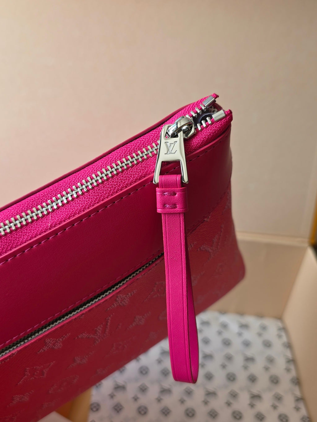 Pink Louis Vuitton small bag with metal zipper pull and attached wrist strap.