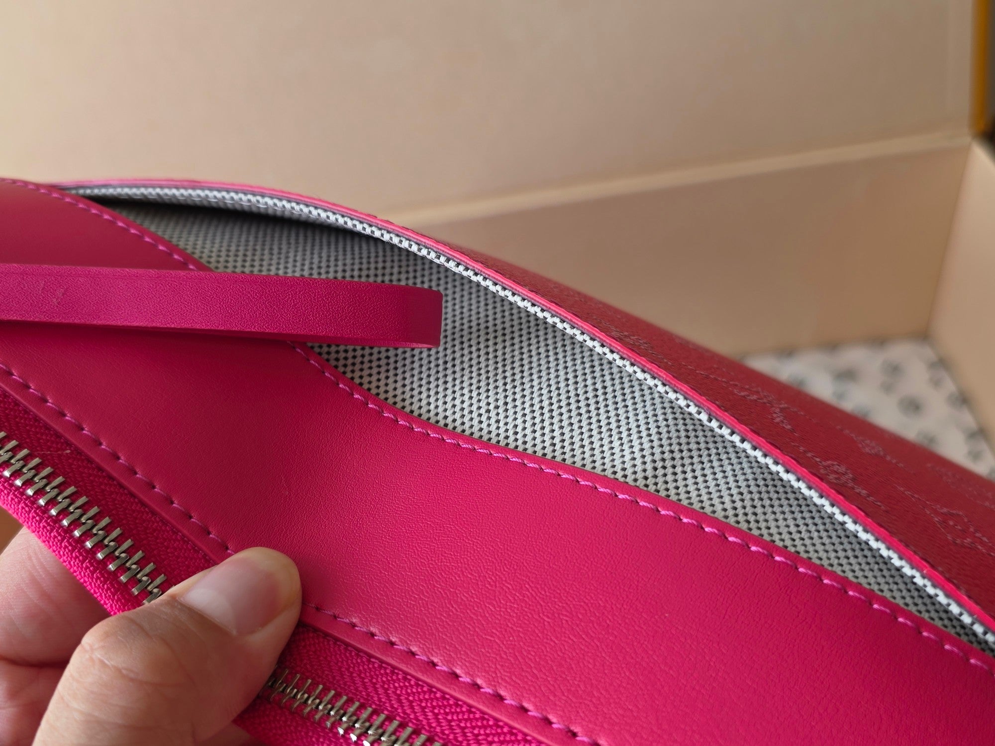 Pink Louis Vuitton small bag interior with zipper track and stitched seam details.