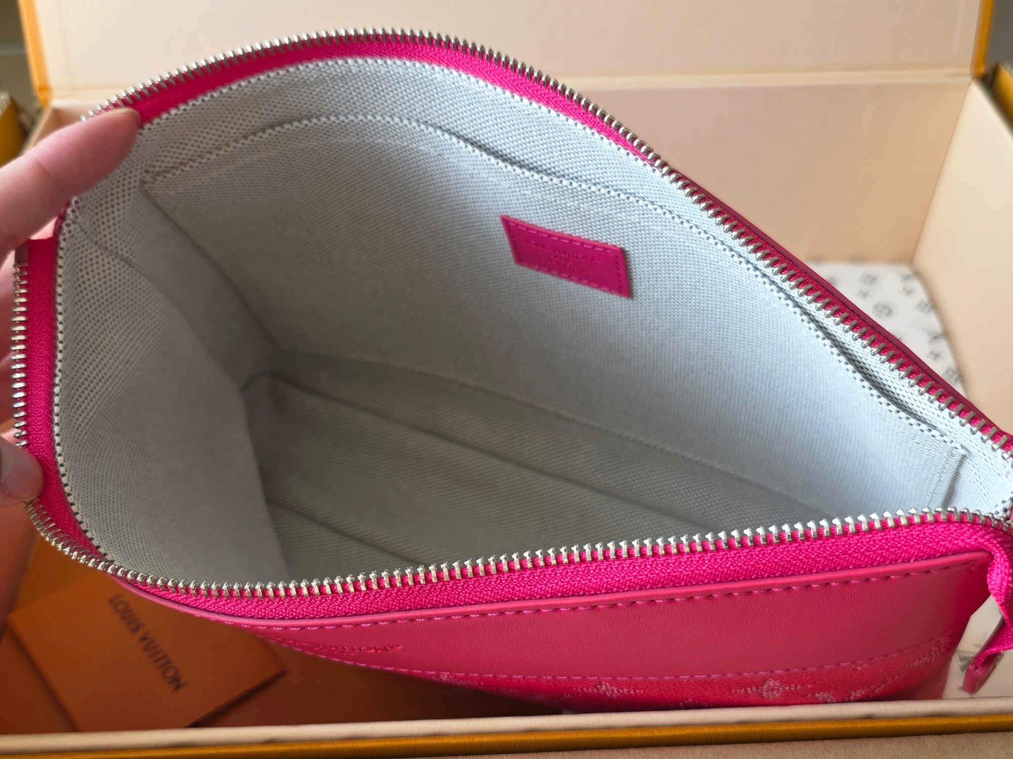 Open pink Louis Vuitton small bag interior with zipper, light lining, and pink trim.
