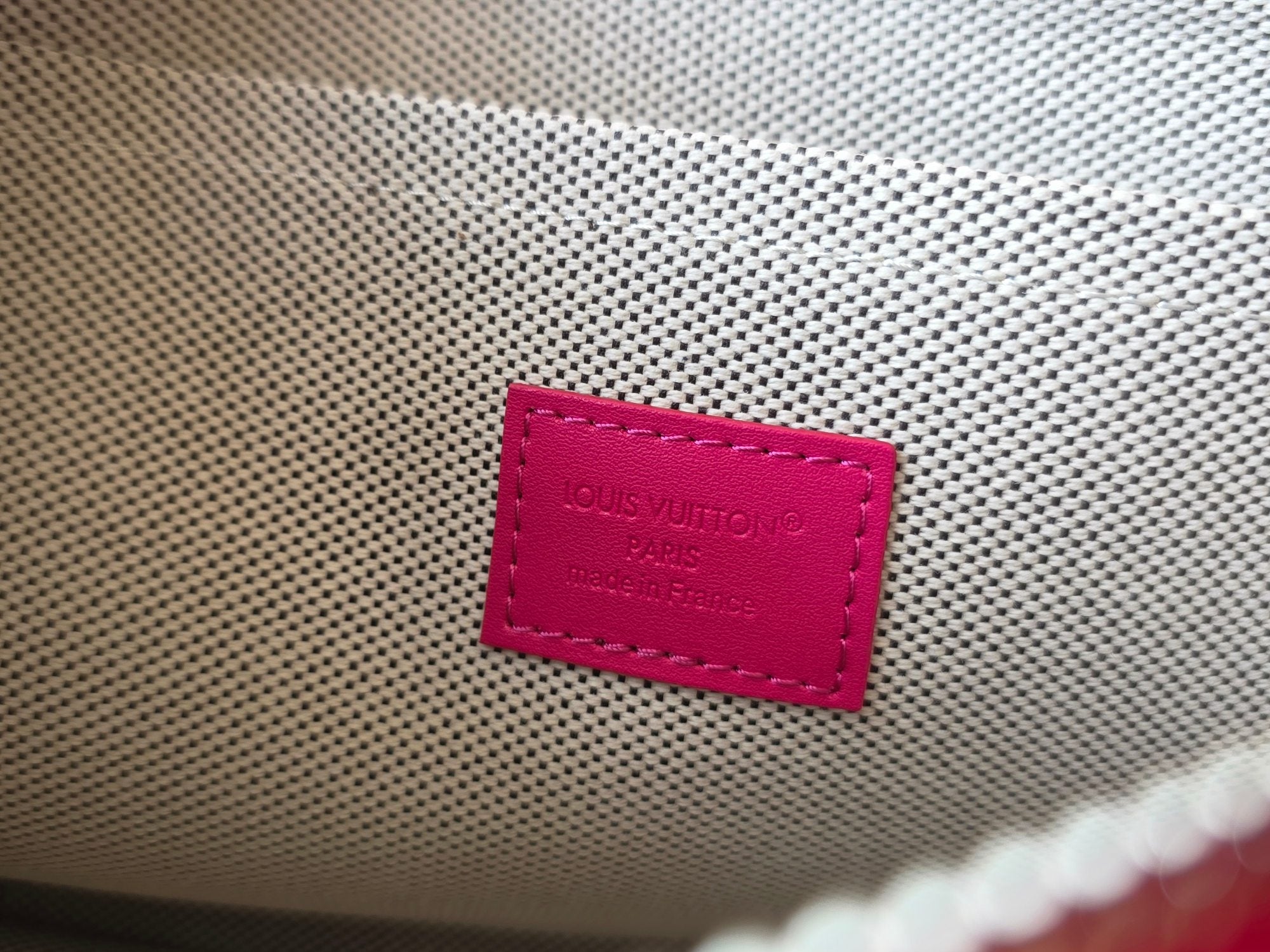Louis Vuitton pink fabric tag with brand lettering on inner bag lining