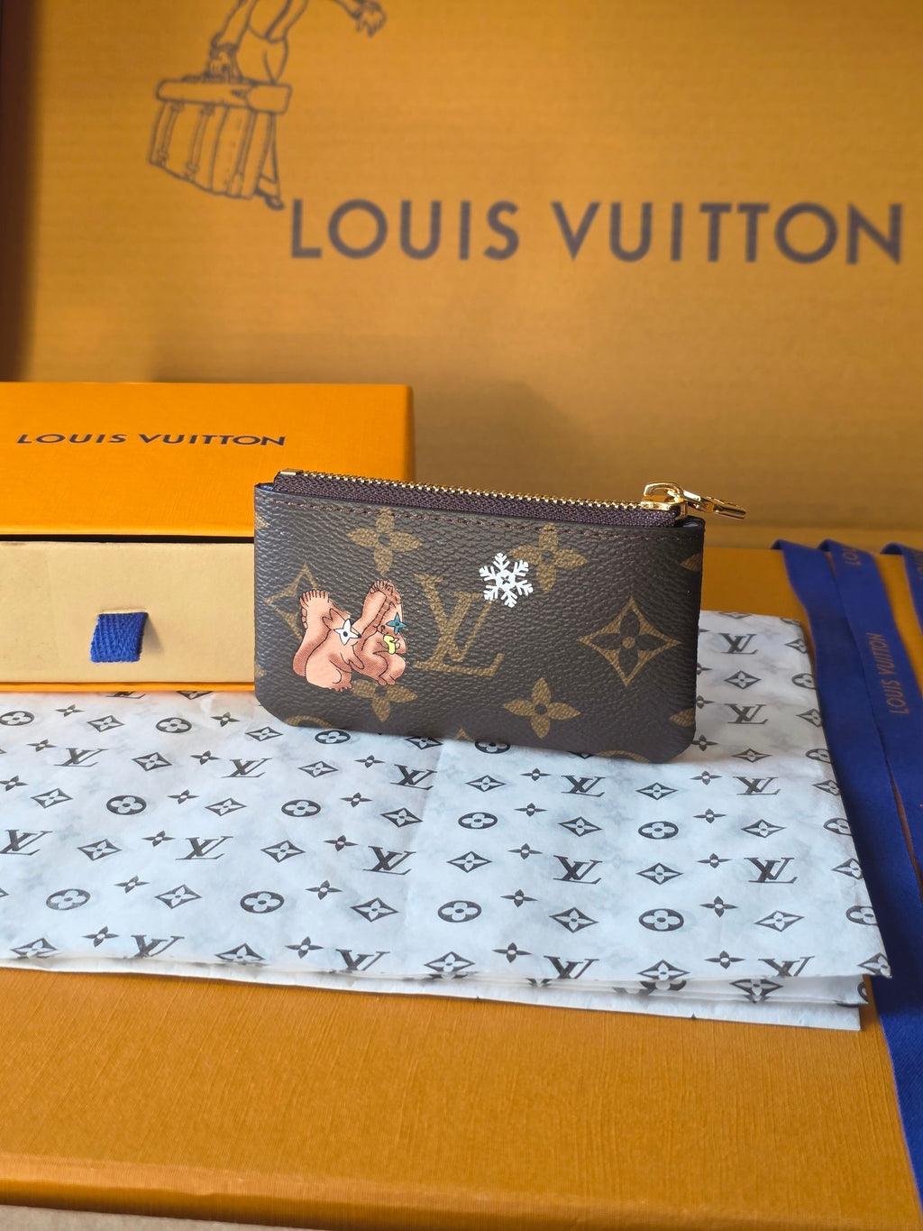 Louis Vuitton small bag with zip closure, monogram pattern and cartoon character graphic.