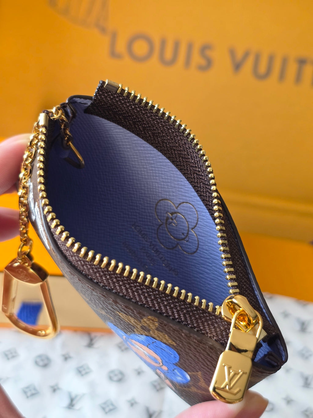 Louis Vuitton small bag close-up with gold clasp and blue inner lining detail.